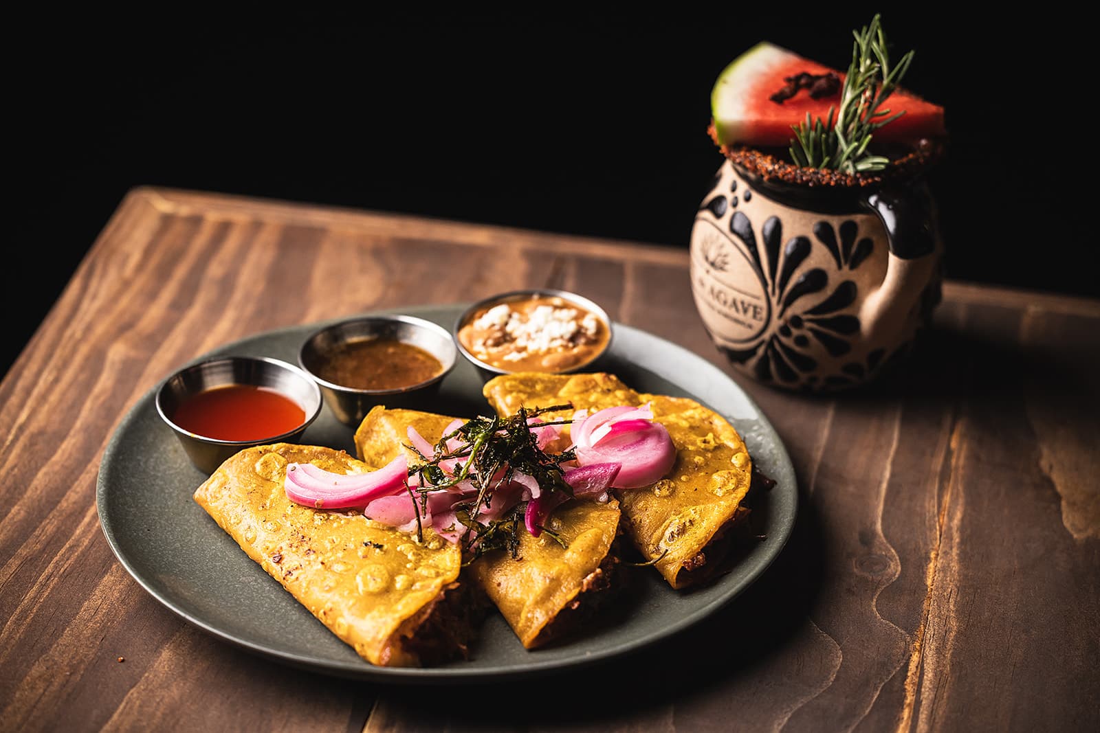 Birria tacos with consommé and colorful house salsas