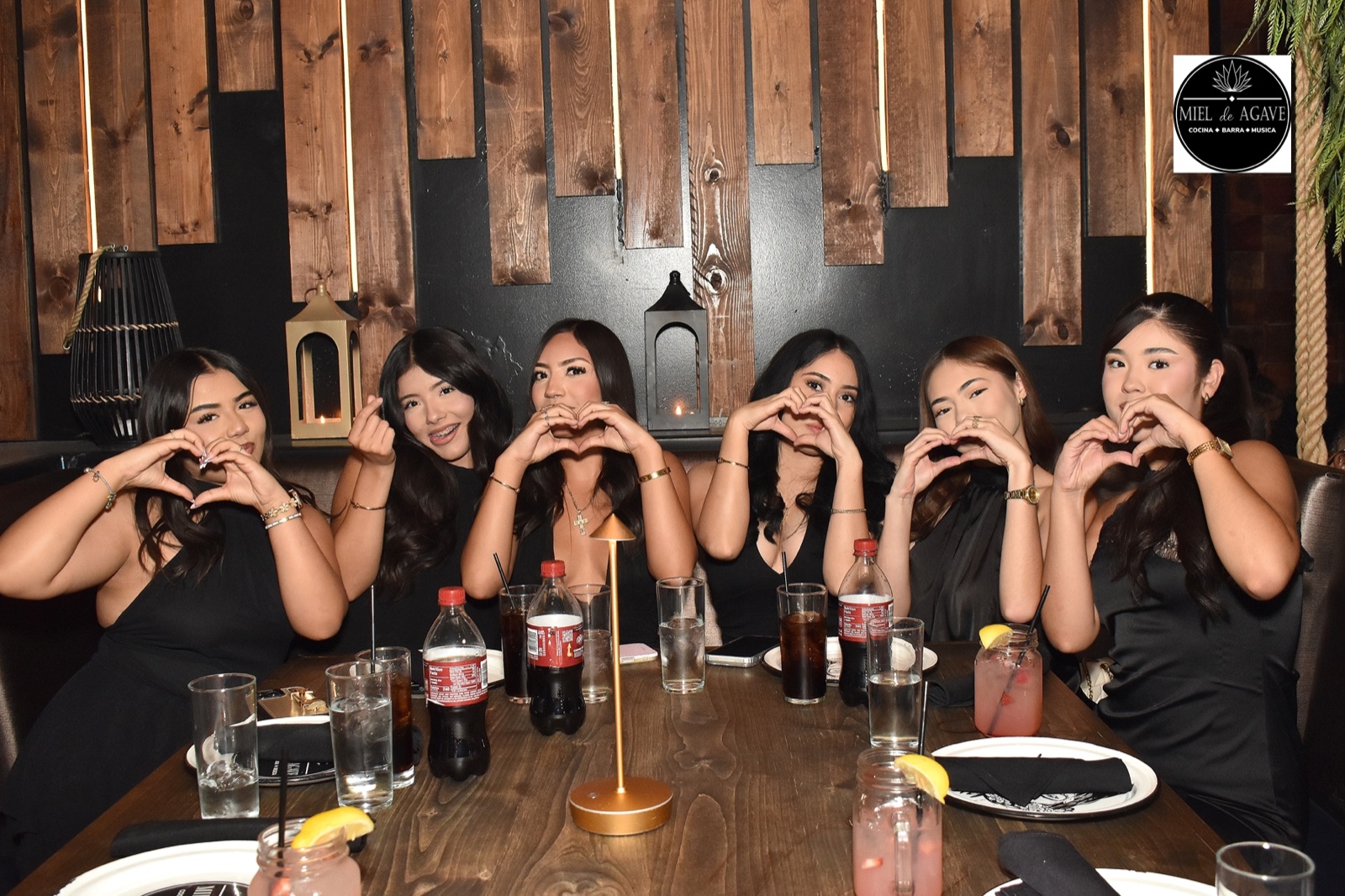 Friends celebrating together and making heart signs at Miel de Agave